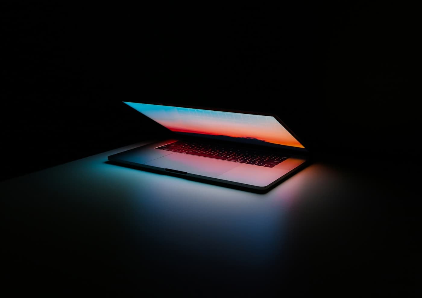 Laptop acceso nel buio con riflessi caldi sullo schermo